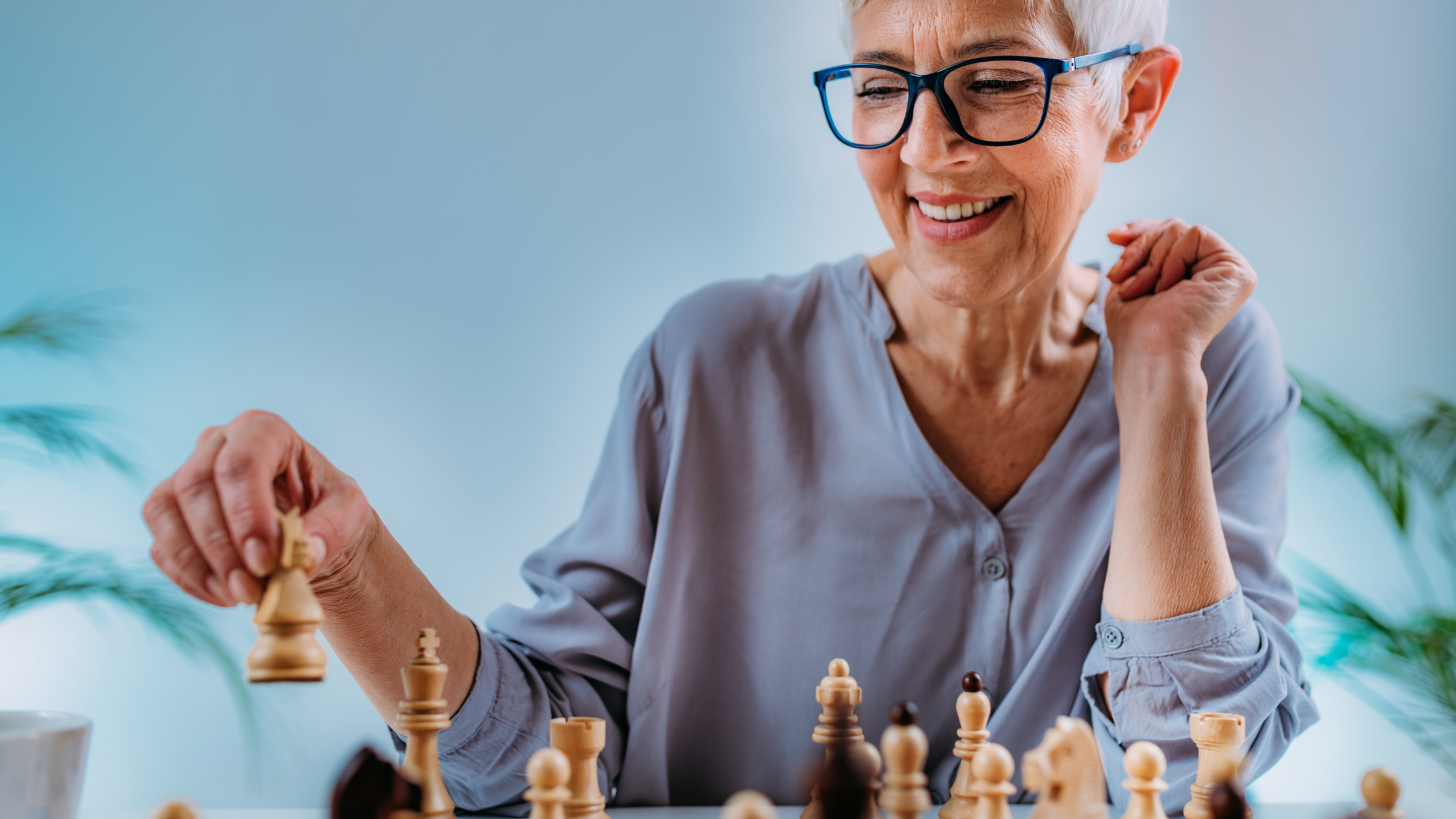 An older woman enjoys a game of chess, staying sharp and avoiding cognitive decline through mental stimulation.